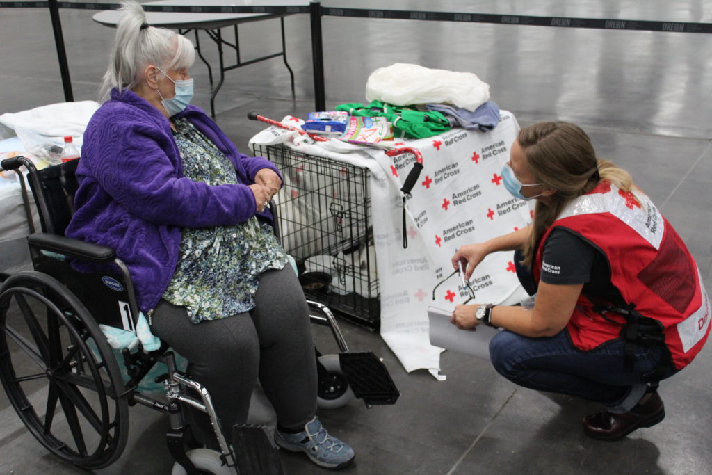 Kathie Tapia shows her two cats to a Red Cross volunteer at the Oregon Convention Center after being forced from her home due to wildfires in Clackamas County, Oregon. Photo by Axl David/American Red Cross.