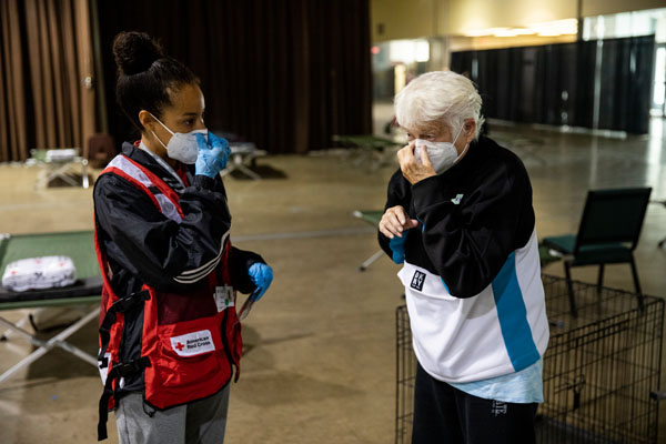 Leslie Sierra of the American Red Cross shows Juanita Ann Hamann how to put on a mask at a Red Cross shelter, in Salem, OR on Sept. 15, 2020. Photo by Scott Dalton/American Red Cross.